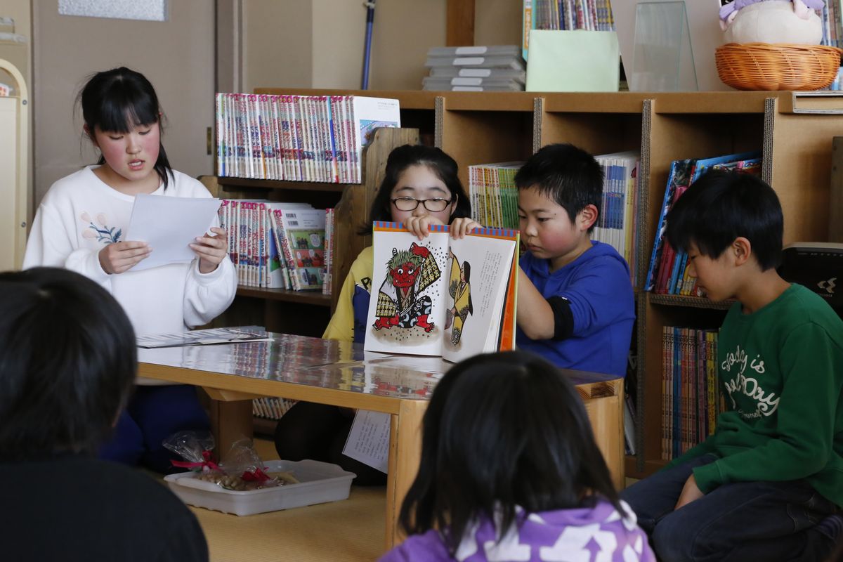 図書室で節分に関する本の読み聞かせを行う児童たち