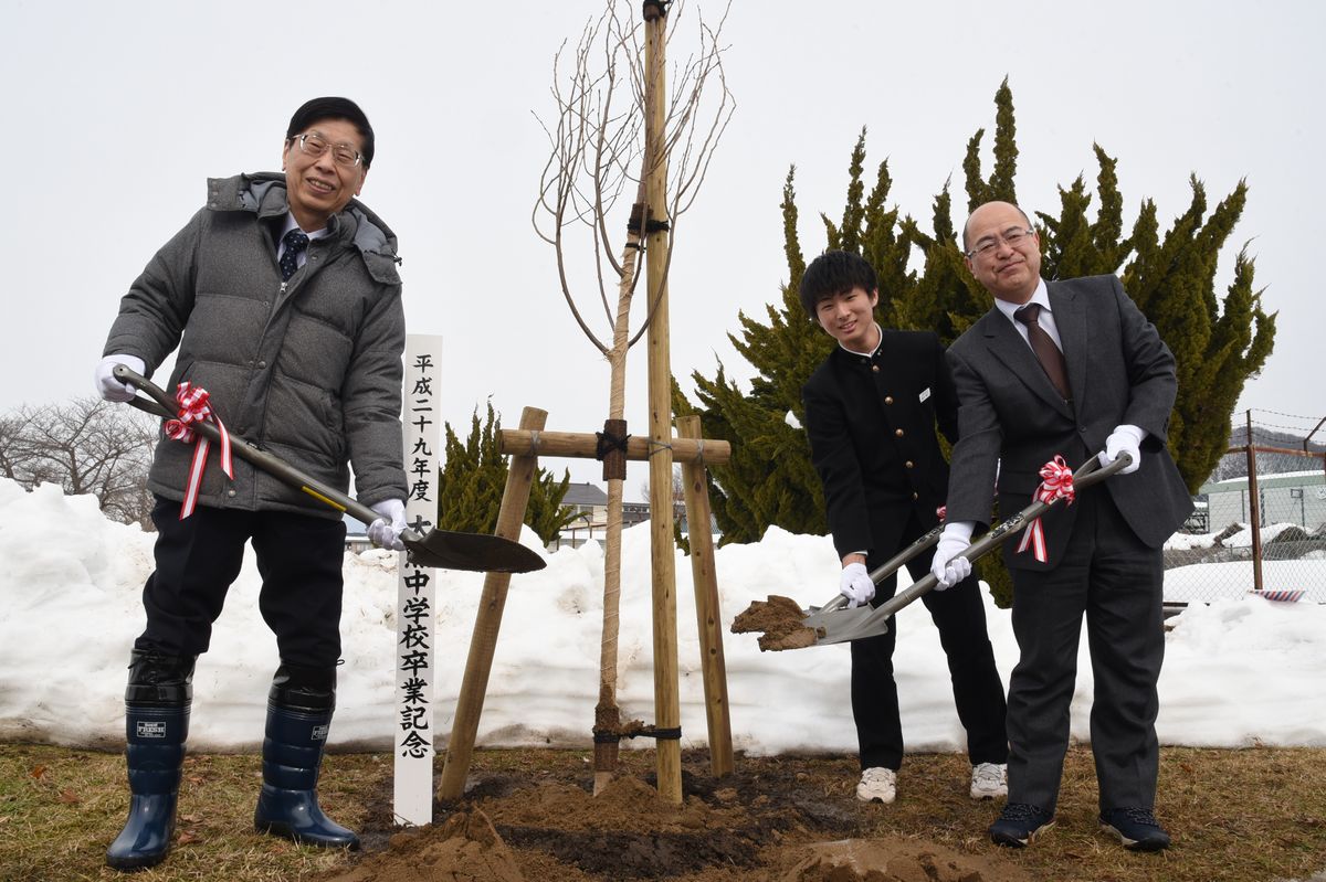 記念樹を囲み笑顔で植樹する卒業生ら