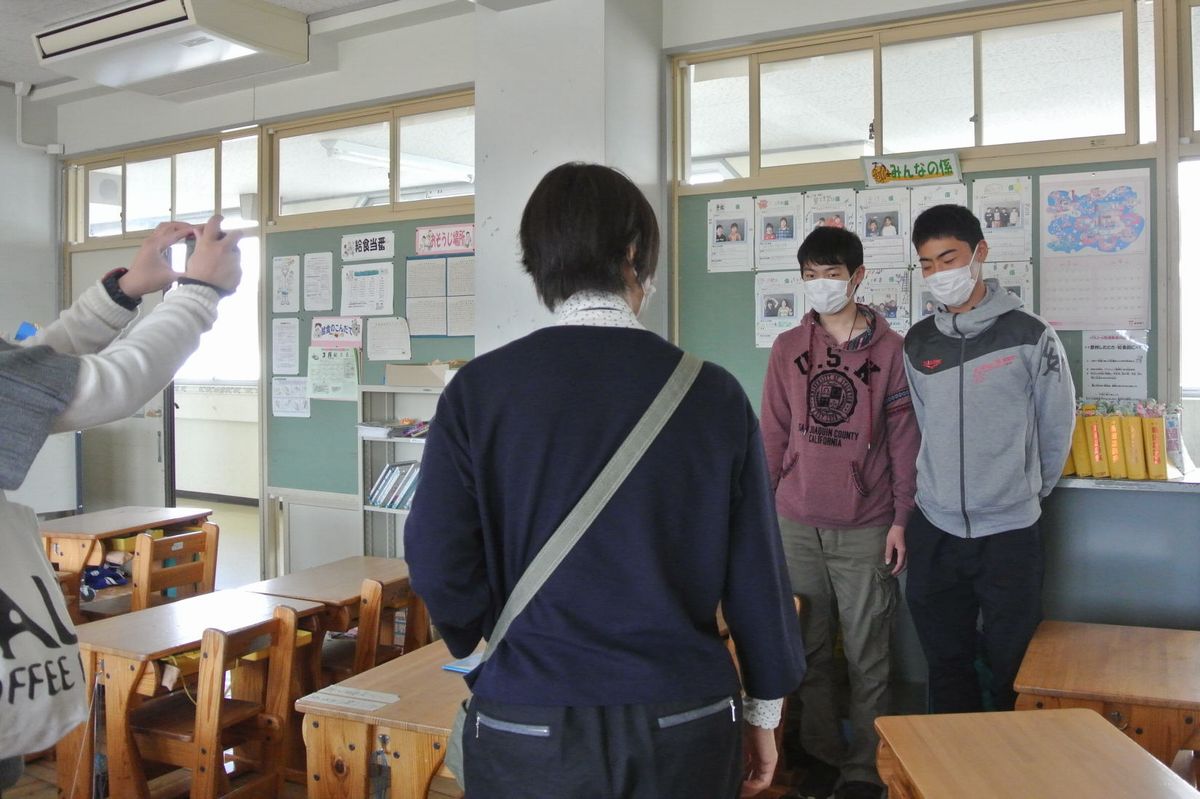 校舎内で偶然同級生と再会し喜び合う二人