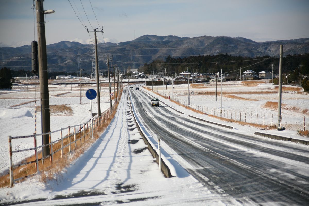 雪の積もった道路を往来する乗用車