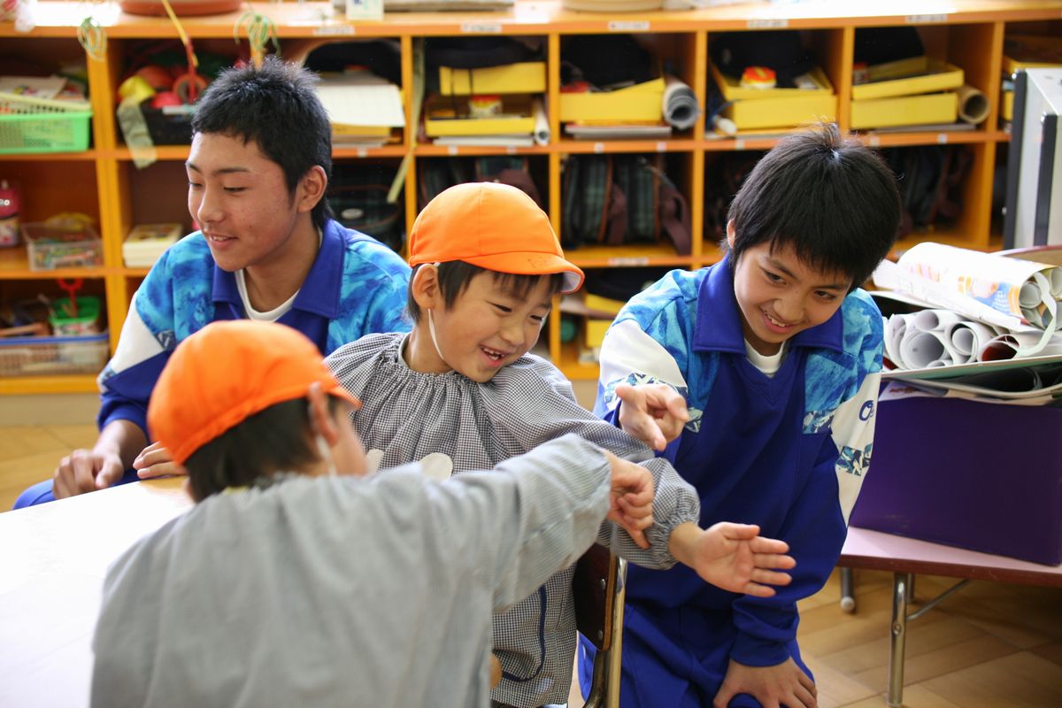 部屋の中でじゃんけんをして遊ぶ園児と中学生