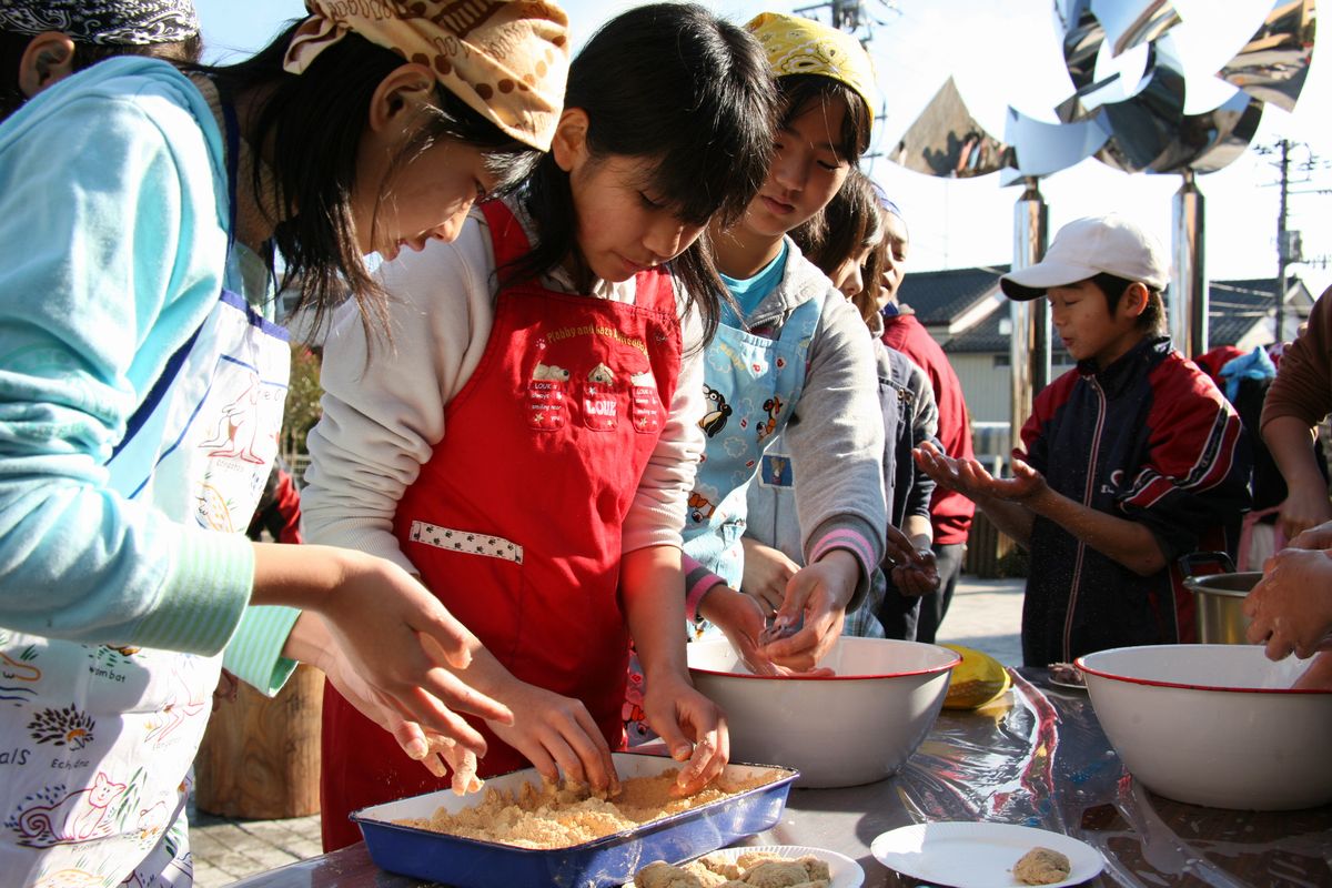 自分たちでつきあげた餅をちぎって、きな粉を付ける子どもたち