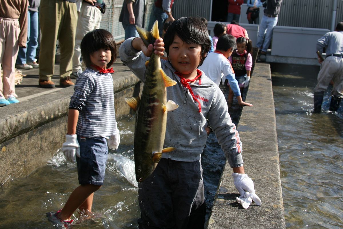 鮭のつかみ取りで見事大物をつかまえた男の子