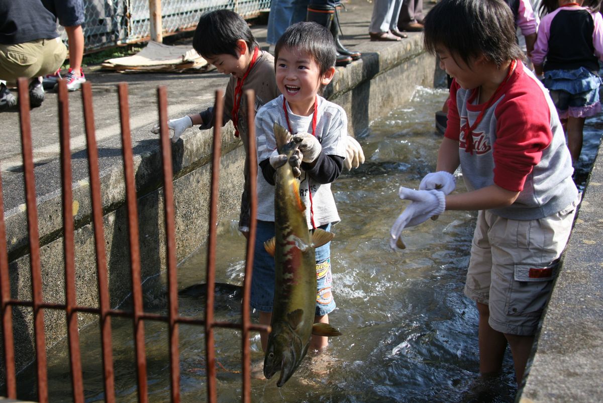 つかみ取りで大きな鮭をつかまえてとても嬉しそうに笑う男の子