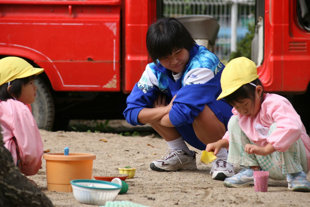 園児と砂遊びをする生徒