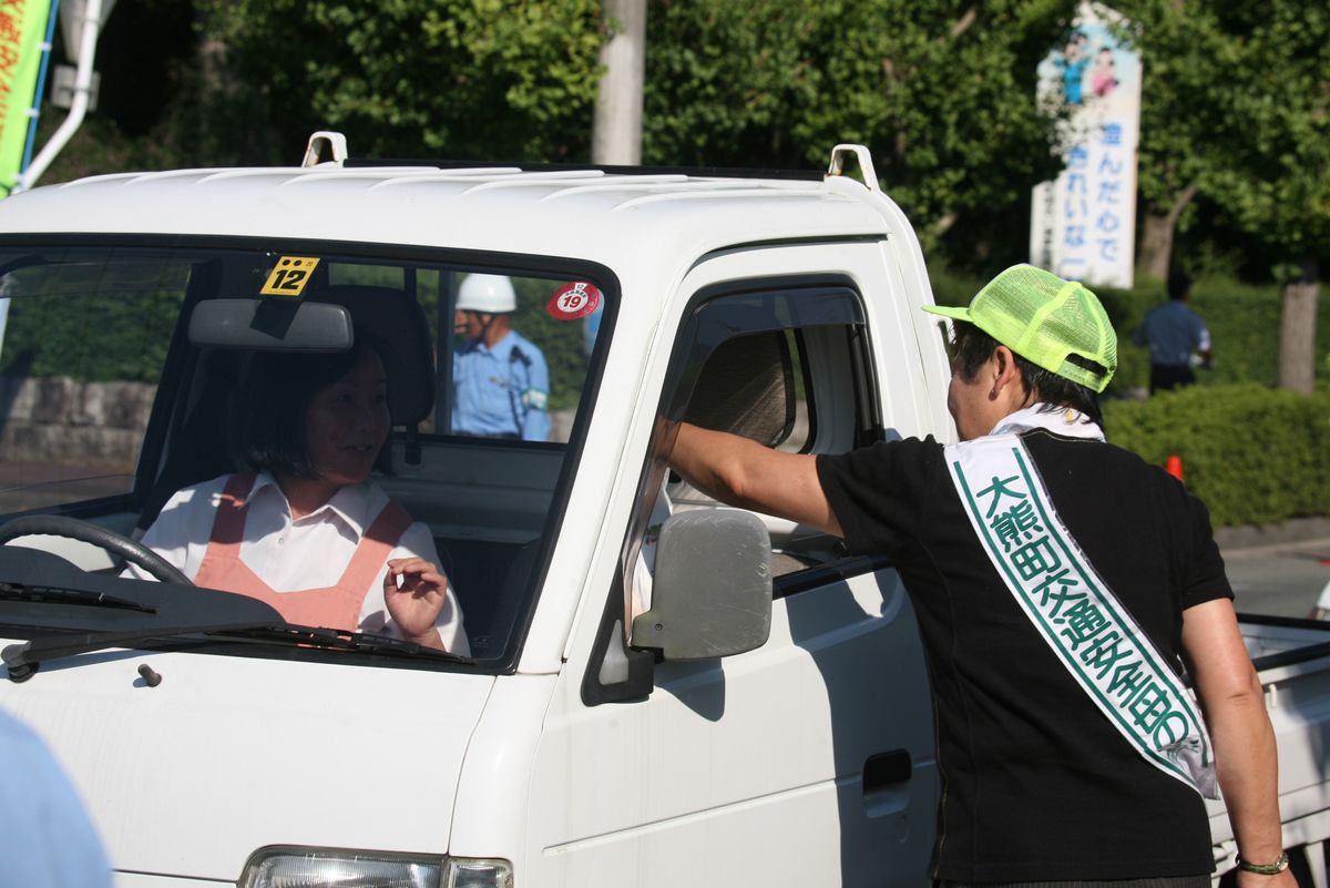 県道を走行するドライバーに交通事故防止を呼び掛ける参加者