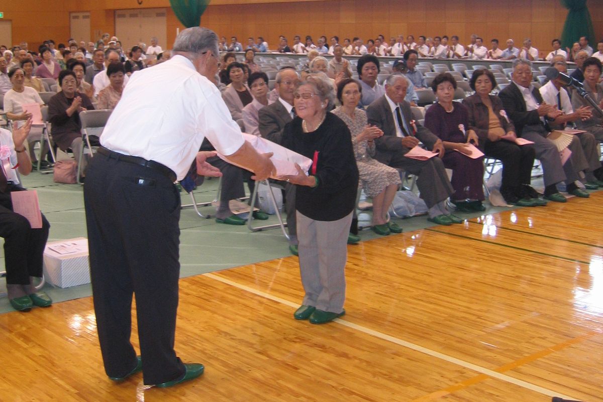 志賀町長から記念品を贈られるお年寄り