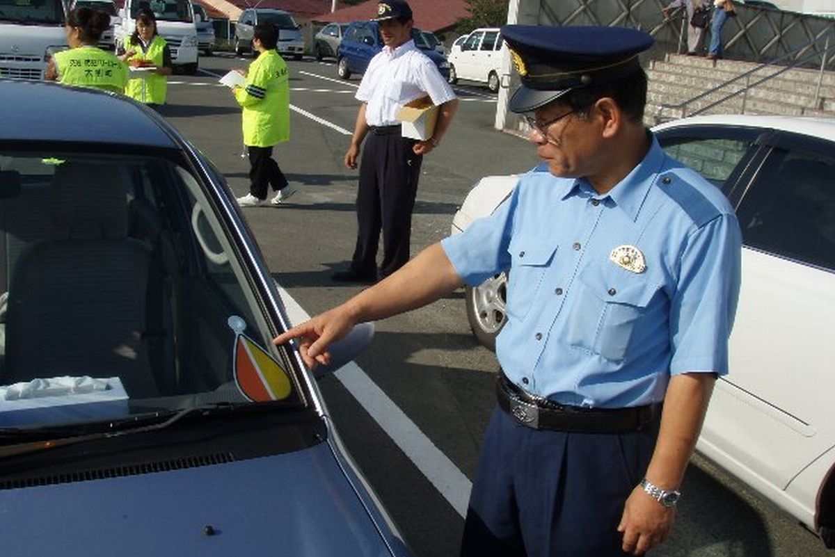 高齢ドライバーの自動車の「もみじマーク」をチェックする警察官