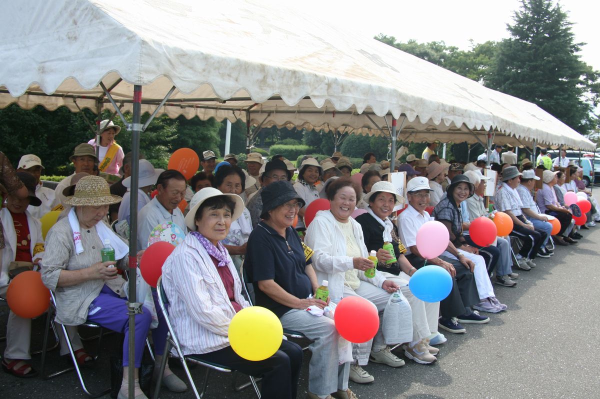 役場玄関前で行われた伝達式に参加した関係者ほか老人クラブ会員約30人