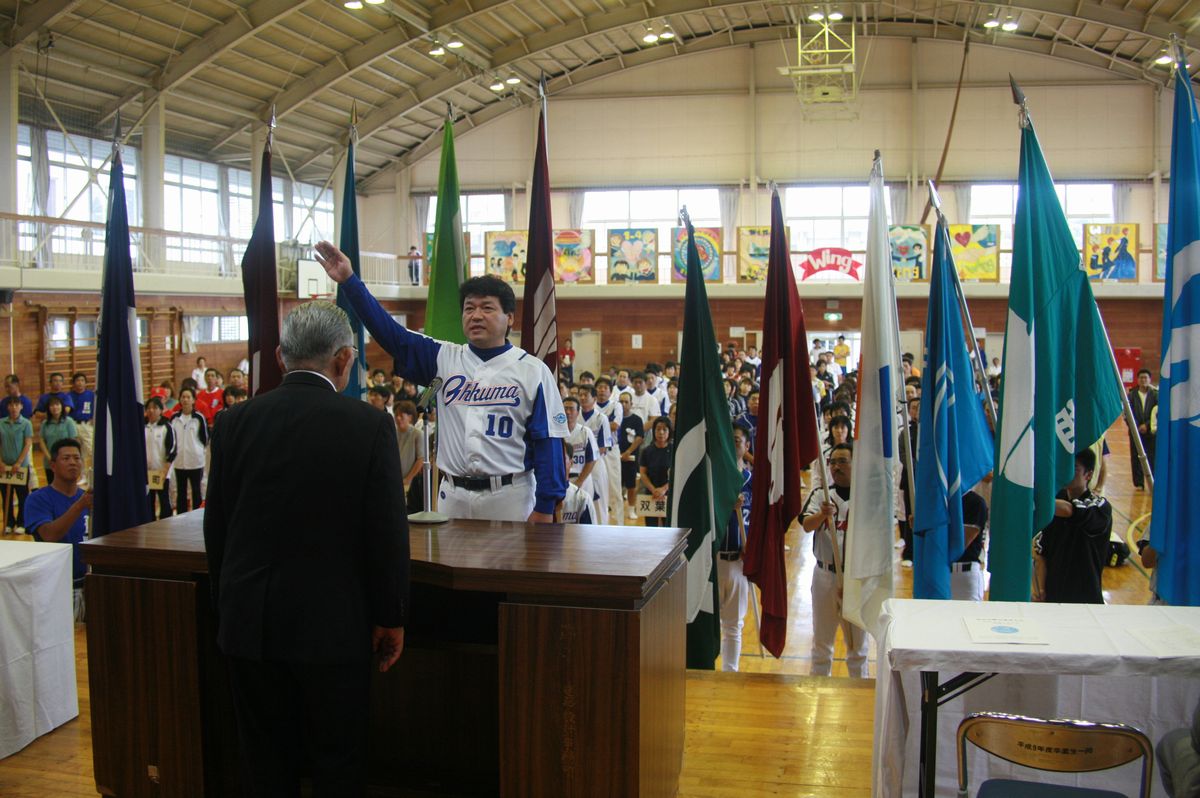 開会式で選手宣誓をする大熊町チームの代表とそれを囲む各市町村旗を掲げる選手たち