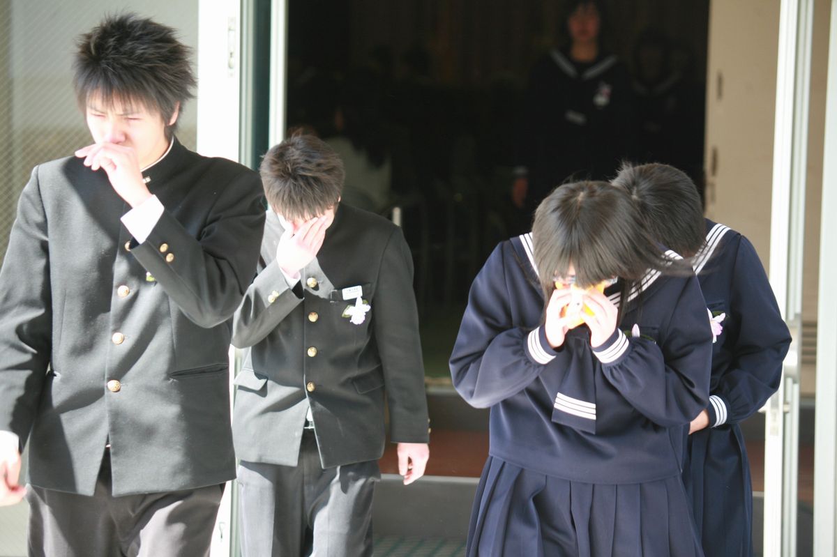 涙を拭いながら式場を後にする卒業生たち