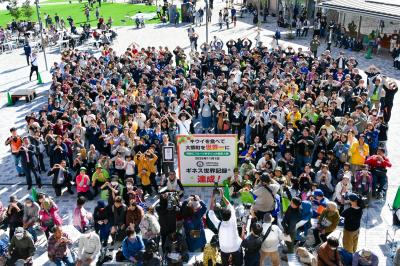 11月1日、駅西交流エリアでグランドオープン後初となる「ふるさとまつり」が開催され、約1,800人の来場者で賑わいました。イベントではギネス世界記録への挑戦も行われ、写真は記録達成を喜ぶ参加者の皆さんが両手でポーズをとる様子を上空から撮影したものです。