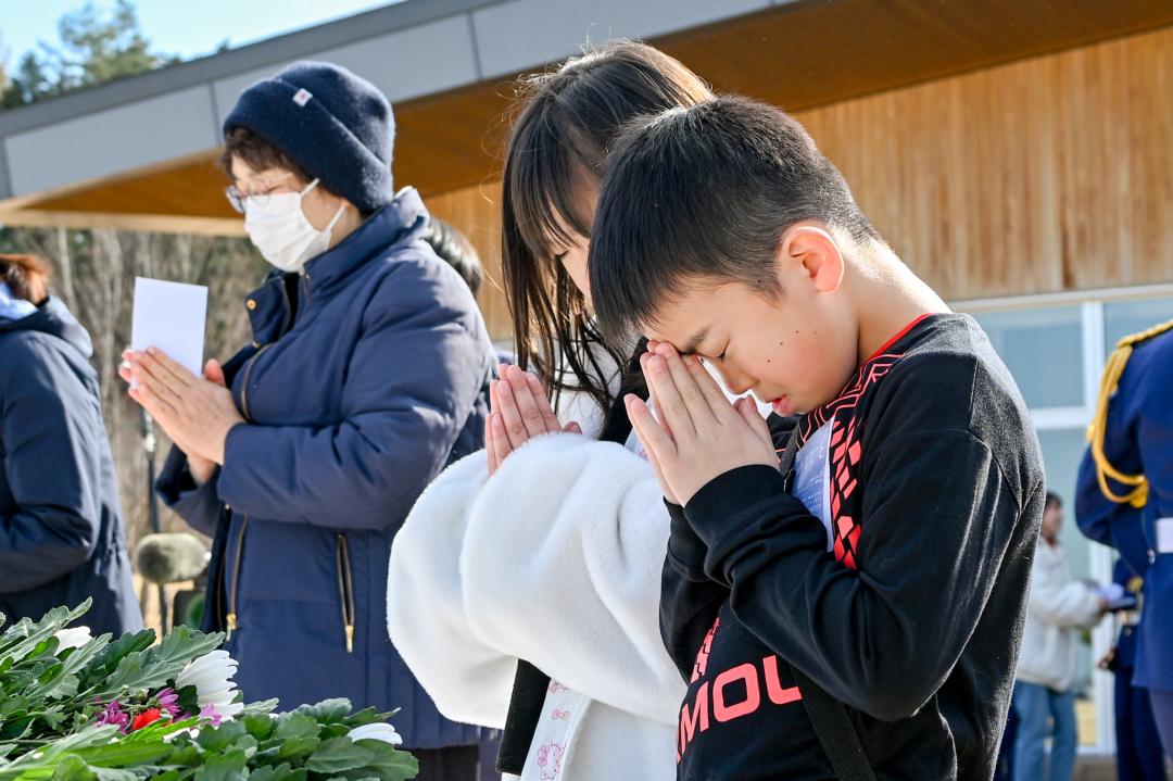 献花台に向かい、そっと手を合わせる参加者