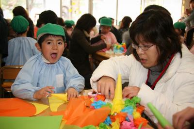 節分の鬼の冠に付けるツノをお母さんと一緒に作る園児