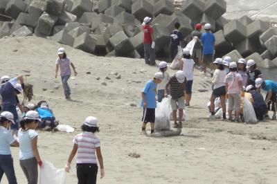 海岸に捨てられた空き缶、空き瓶や花火の燃えかすなどを丁寧に拾い集める児童