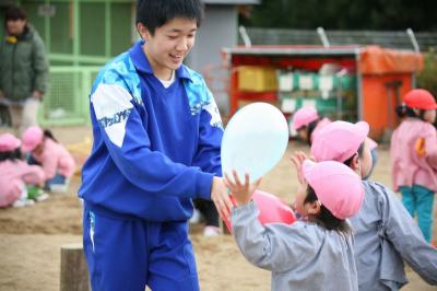 中学生のお兄さんと風船で遊ぶ園児