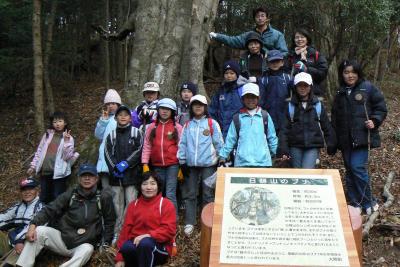 日隠山の樹齢約200年のブナの木をバックに記念撮影する参加者