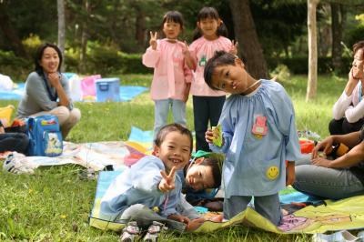 中央台生活環境保全林の広場でお友だちと仲良くお菓子を食べる園児たち