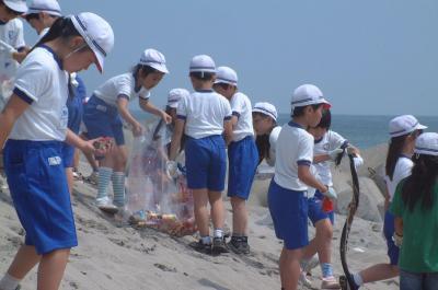 海岸に捨てられた空き缶や木くずなどを拾い集める熊町小学校の4年生