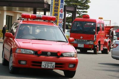 役場前からパレードに出発する広報車、消防車