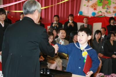 佐藤大右園長から終了証書を受け取り、握手を交わす卒園児